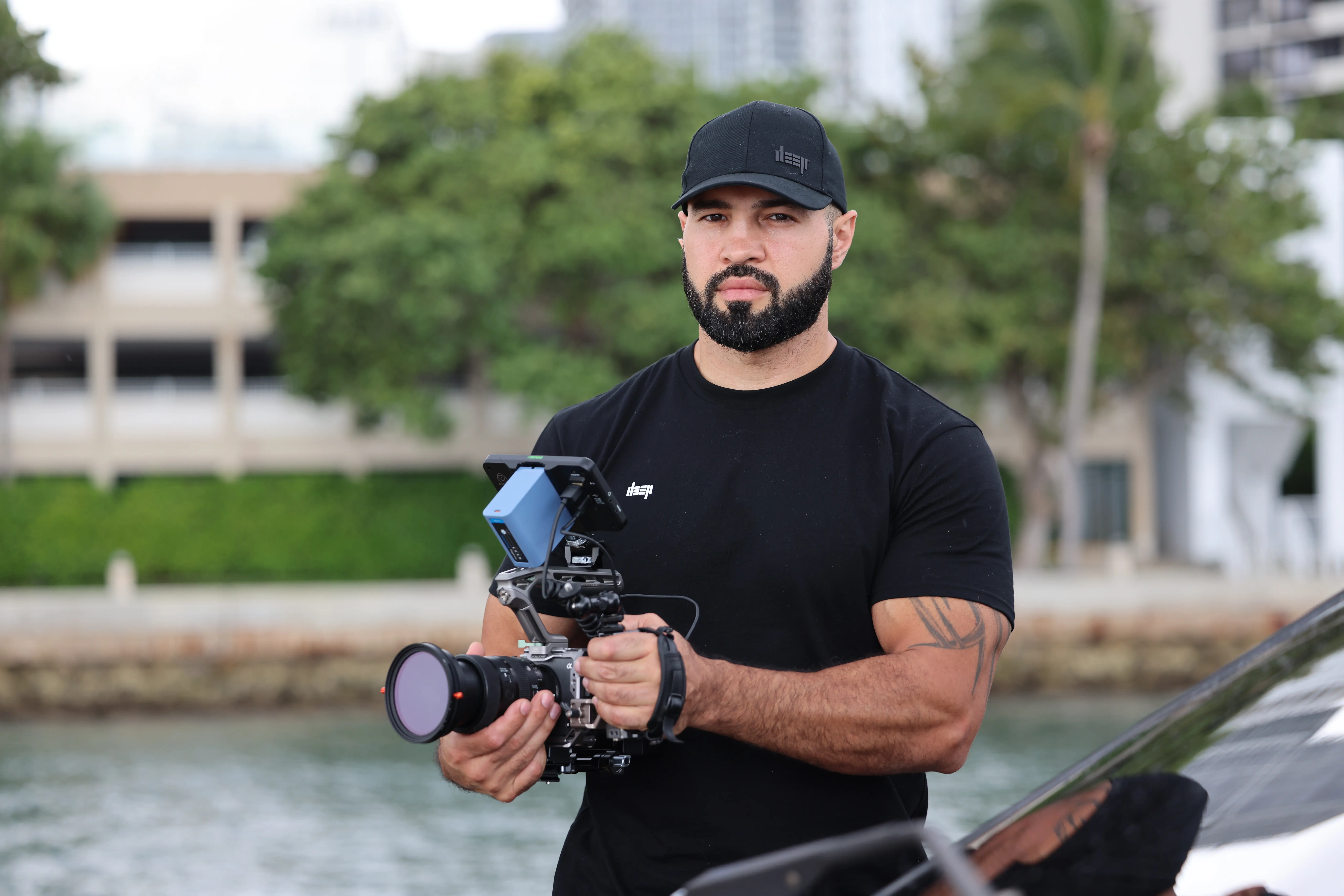 Miami videographer holding a camera on a handheld stabilizer beside the water.